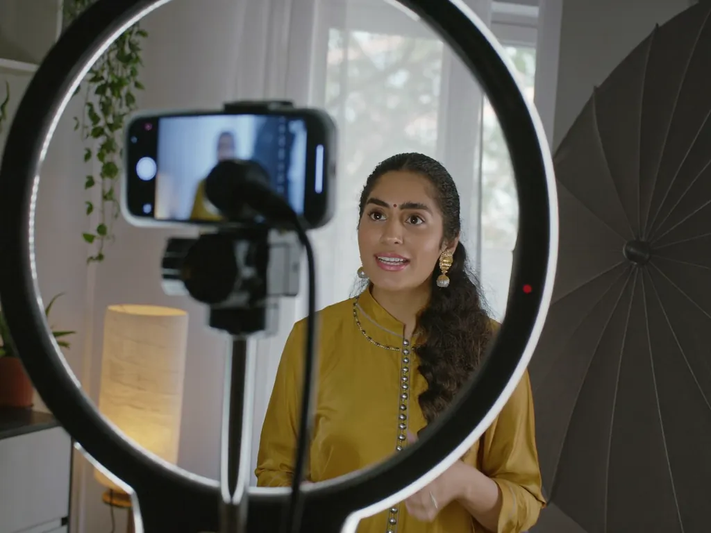 A presenter speaking to a phone camera on a bright home set